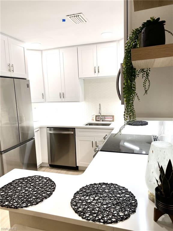 1st floor Kitchen featuring white cabinets, appliances with stainless steel finishes, light countertops, and open shelves