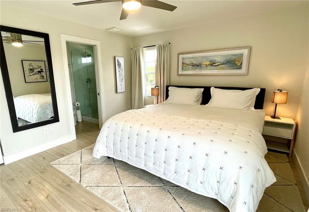 Bedroom featuring ensuite bathroom, wood finished floors, and a ceiling fan