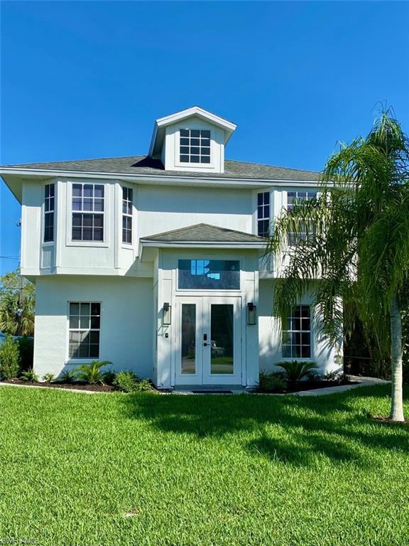 View of front facade featuring a front yard, french doors, and stucco siding