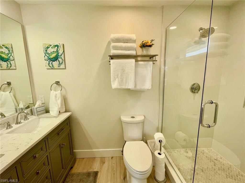 Bathroom with double vanity, a stall shower, and light wood finished floors