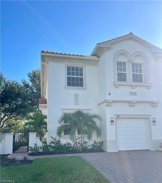 Mediterranean / spanish-style house featuring a tile roof, stucco siding, and an attached garage