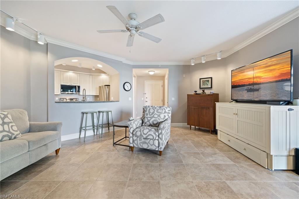 Living area with rail lighting, ornamental molding, arched walkways, and a ceiling fan