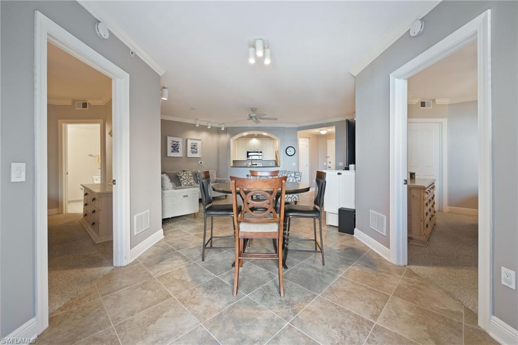 Dining space featuring light colored carpet, ornamental molding, light tile patterned floors, and ceiling fan
