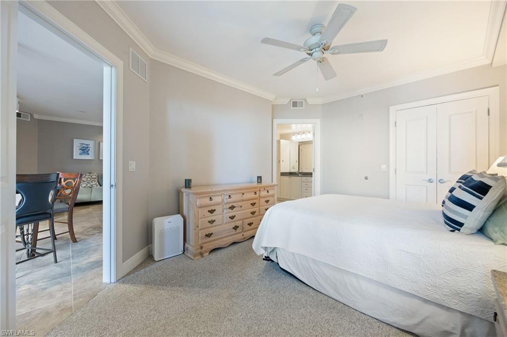 Bedroom with light carpet, ornamental molding, a closet, ceiling fan, and ensuite bath