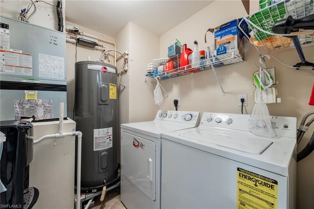 Laundry area featuring electric water heater, washer and dryer, and heating unit