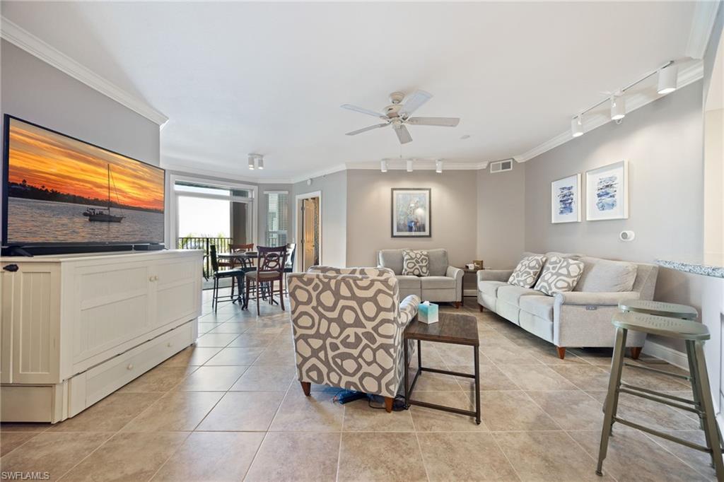 Living room featuring track lighting, crown molding, light tile patterned flooring, and ceiling fan