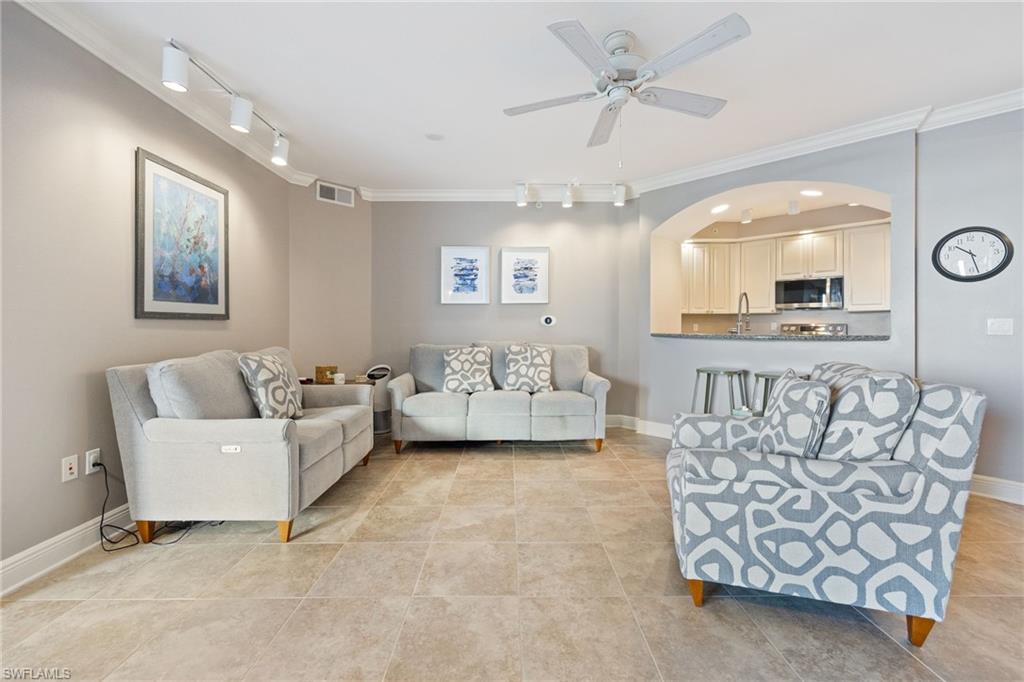 Living room with track lighting, ornamental molding, a ceiling fan, and light tile patterned floors