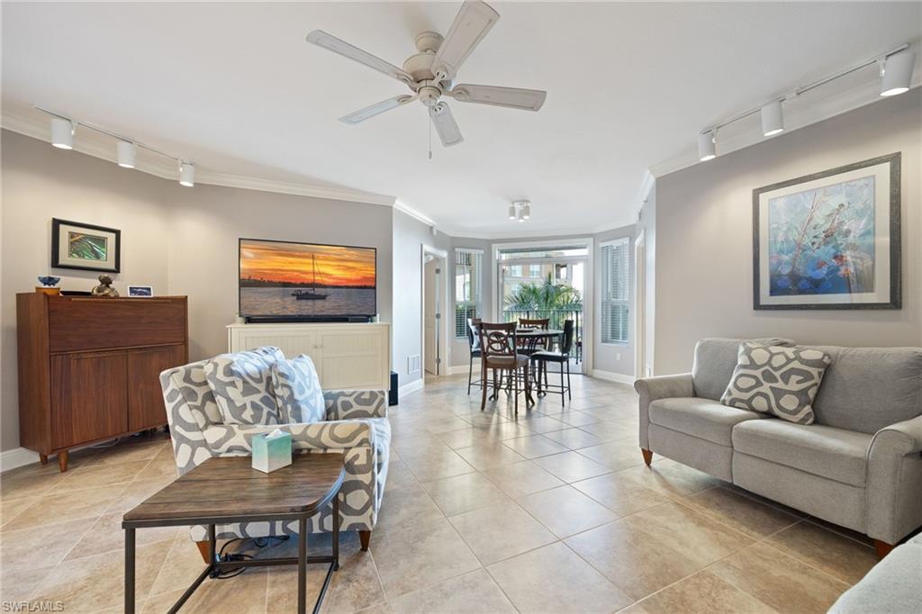 Living room with track lighting, crown molding, ceiling fan, and light tile patterned floors