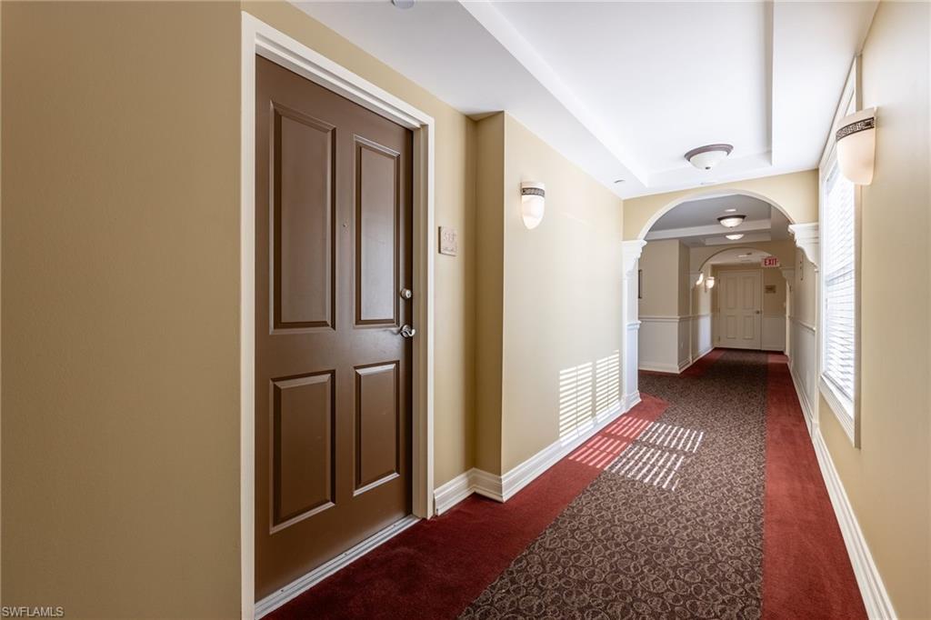 Hallway featuring arched walkways and dark colored carpet