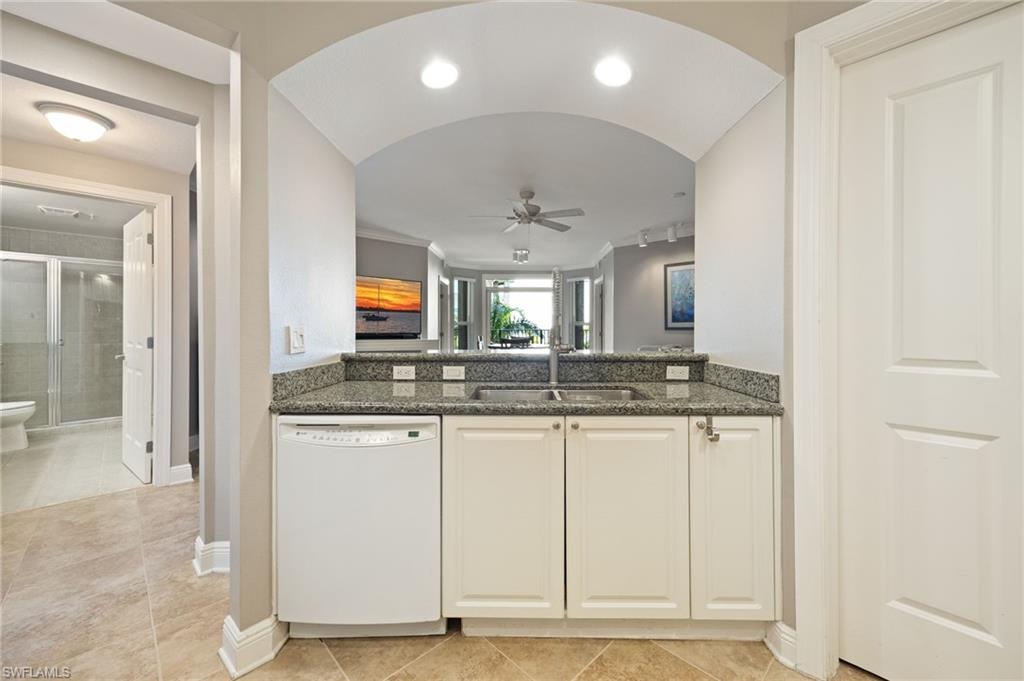 Kitchen featuring dishwasher, ceiling fan, dark stone counters, white cabinetry, and light tile patterned floors