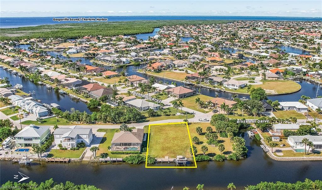 Aerial view of residential area with a large body of water and property parcel outlined