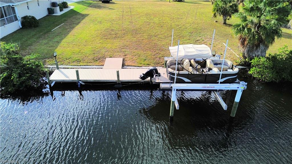 Dock area featuring a water view, boat lift, and a lawn