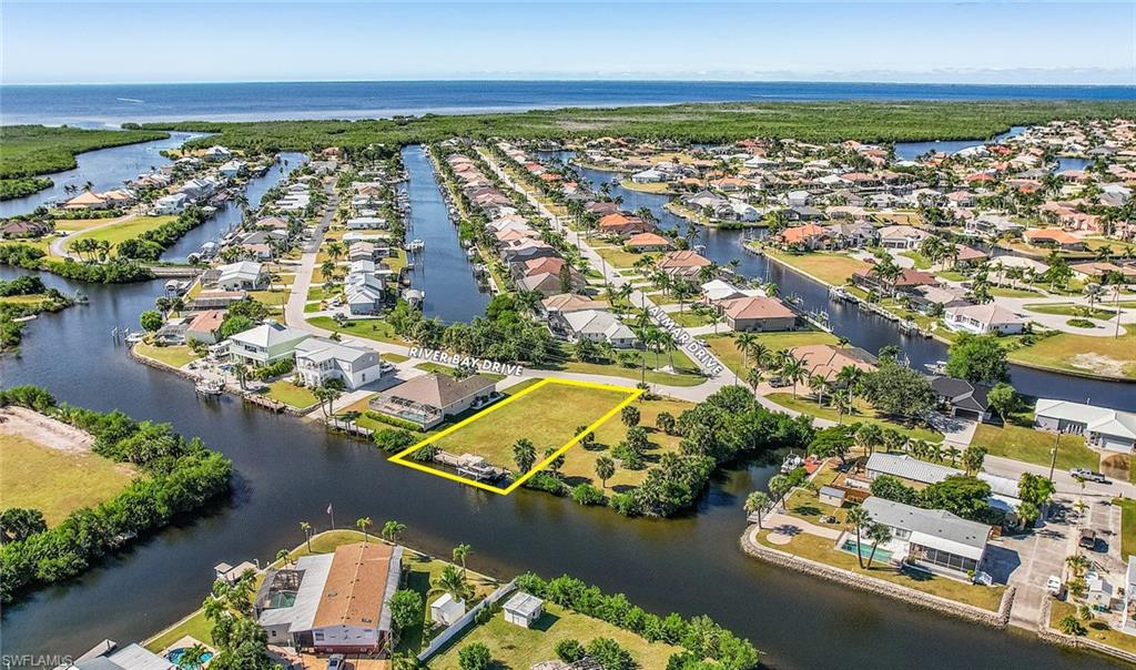 Aerial perspective of suburban area featuring a large body of water and property boundaries highlighted