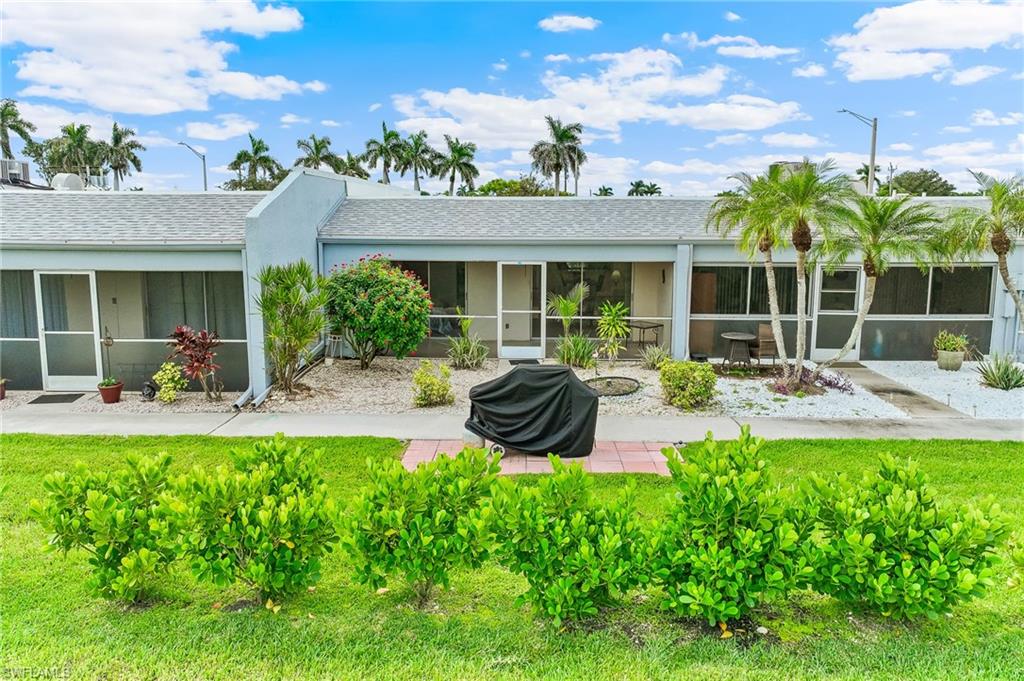 Back of property featuring a sunroom, a yard, a shingled roof, and stucco siding