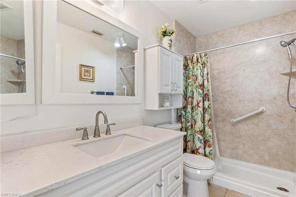 Bathroom with a stall shower, vanity, and light tile patterned flooring