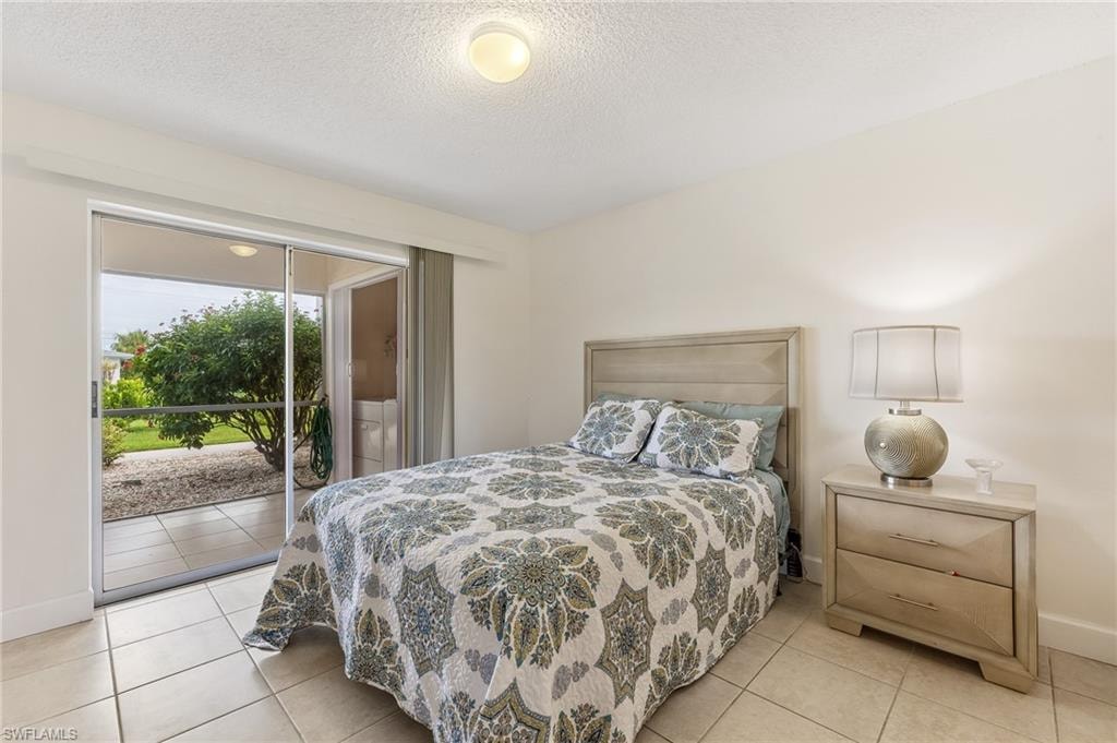 Bedroom featuring access to exterior, a textured ceiling, and light tile patterned flooring