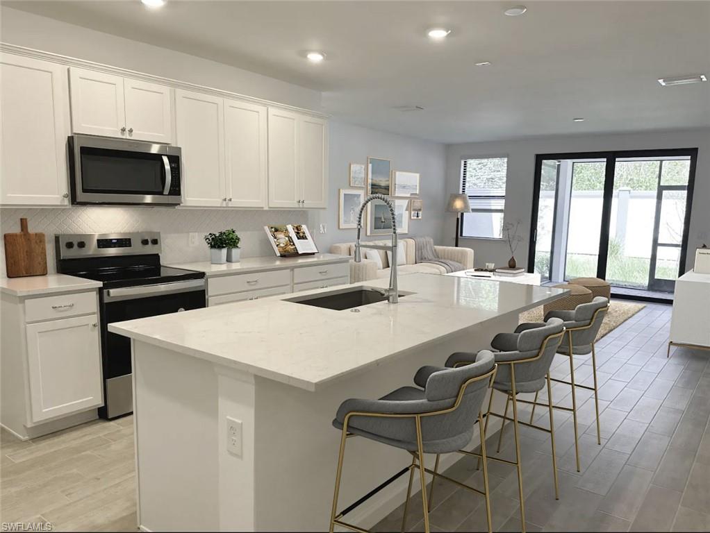 Virtually staged kitchen with appliances with stainless steel finishes, backsplash, wood tiled floors, light stone countertops, and white cabinetry