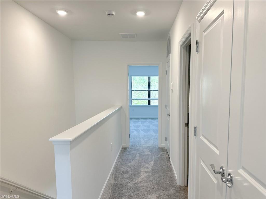 Hall featuring light colored carpet and an upstairs landing