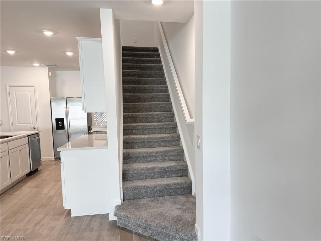 Staircase with recessed lighting and wood finished floors