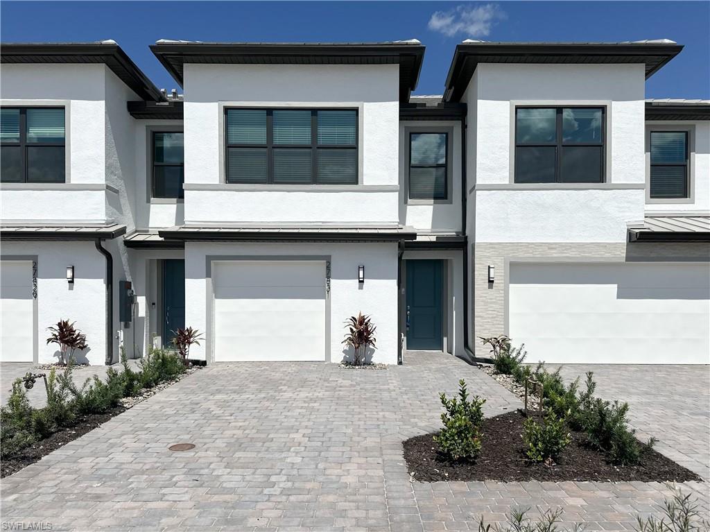 Contemporary home with stucco siding, a garage, and decorative driveway