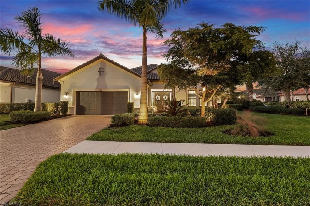Mediterranean / spanish-style home with a lawn, stucco siding, decorative driveway, a garage, and a tiled roof
