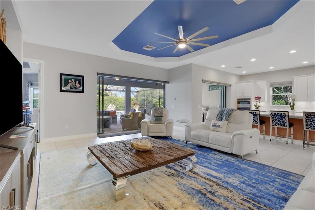 Living room with light tile patterned floors, ceiling fan, and plenty of natural light