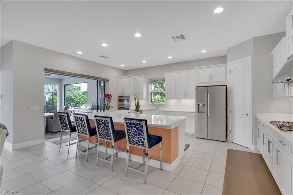 Kitchen featuring stainless steel appliances, a center island, white cabinets, a breakfast bar area, and recessed lighting