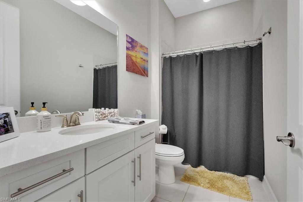 Full bathroom featuring vanity, a shower with shower curtain, and light tile patterned flooring