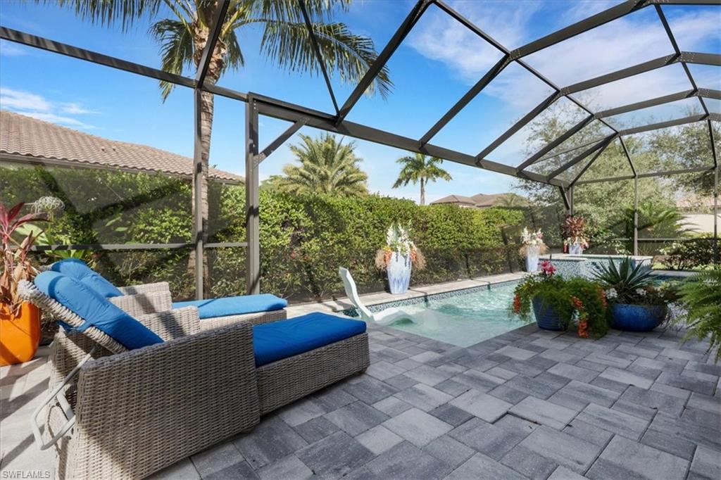 View of pool featuring glass enclosure, a sunroom, and a patio area