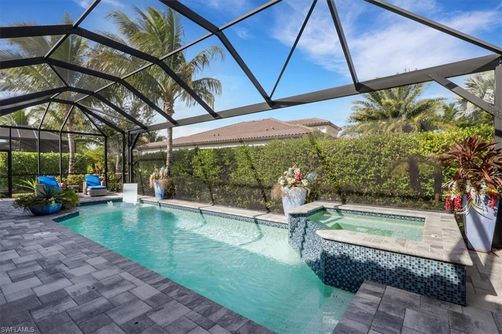 View of pool featuring glass enclosure, a sunroom, a pool with connected hot tub, and a patio area