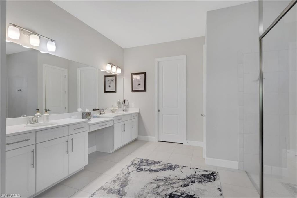 Full bath with two vanities, a shower stall, and light tile patterned floors