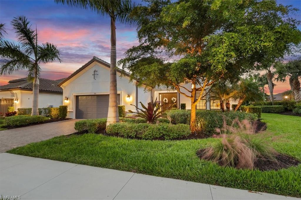 Mediterranean / spanish home featuring an attached garage, stucco siding, a front lawn, and decorative driveway