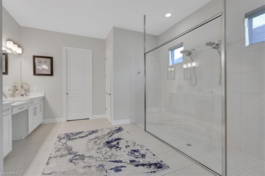 Bathroom featuring vanity, tiled shower, and light tile patterned floors