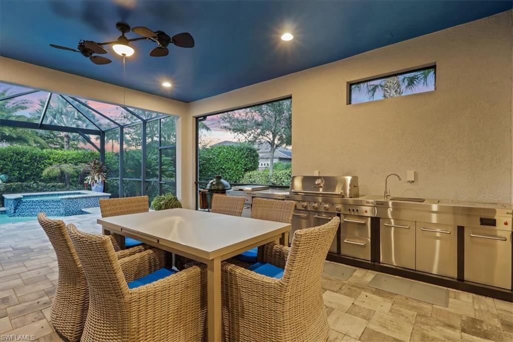 View of patio featuring an outdoor kitchen, a sunroom, outdoor dining area, a pool with connected hot tub, and glass enclosure