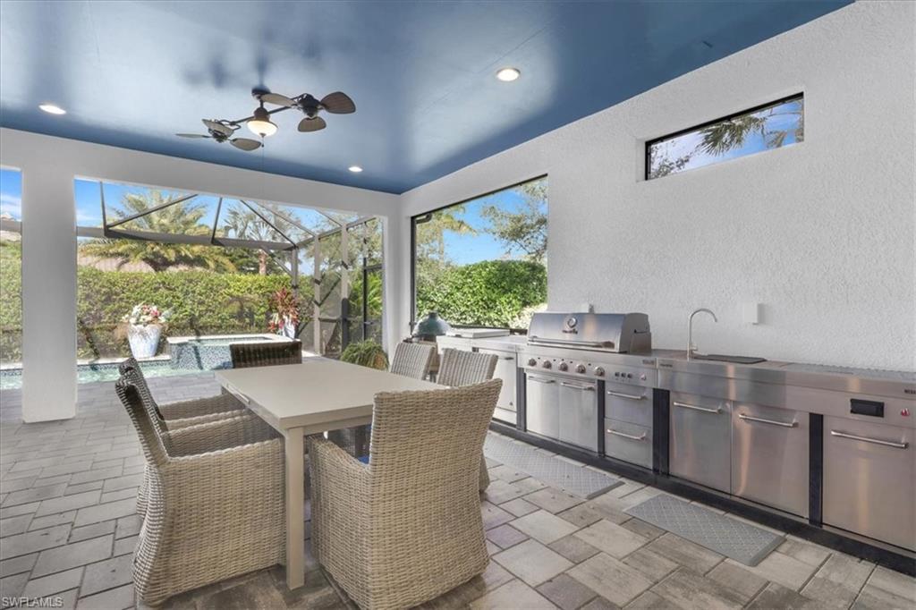 View of patio with area for grilling, outdoor dining space, glass enclosure, a sunroom, and ceiling fan