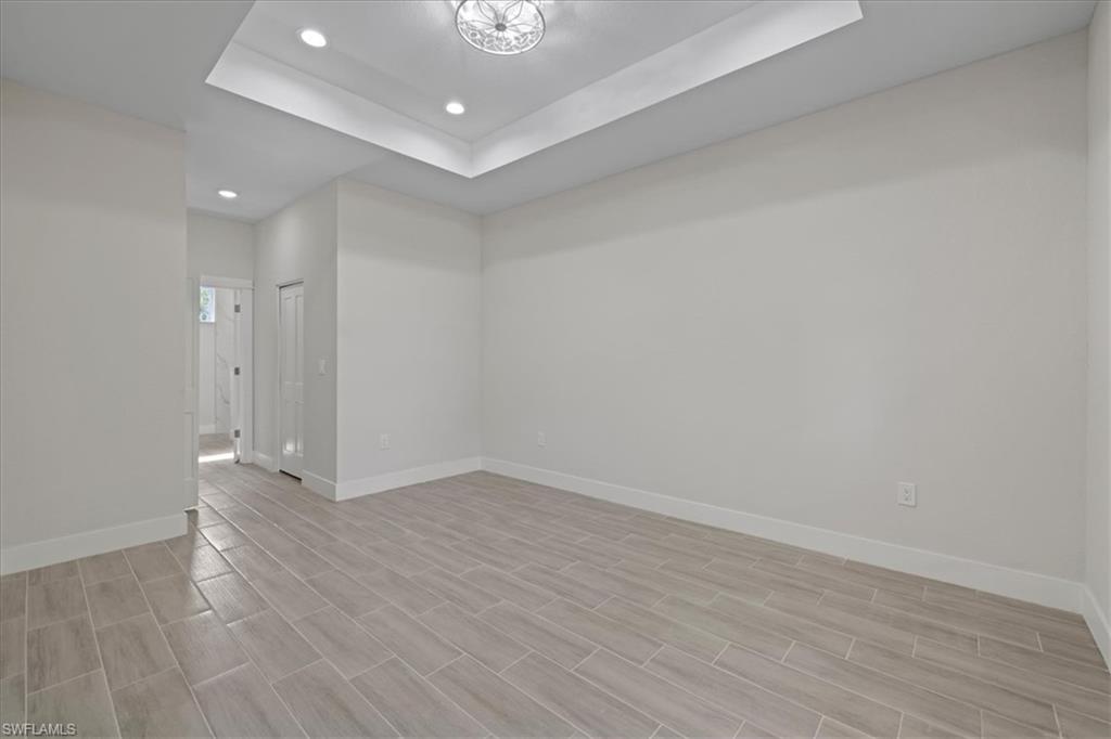 Unfurnished room with a tray ceiling, recessed lighting, and wood finish floors