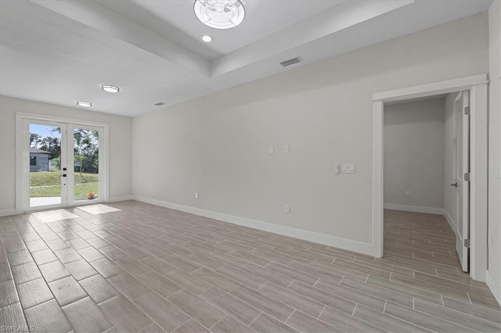 Unfurnished room featuring french doors, wood tiled floors, a tray ceiling, and recessed lighting