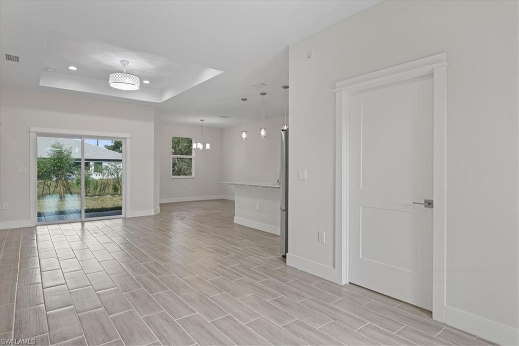 Spare room featuring a chandelier, a raised ceiling, recessed lighting, and wood tiled floors