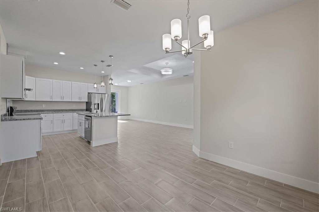 Kitchen with decorative light fixtures, recessed lighting, white cabinets, a kitchen island, and open floor plan