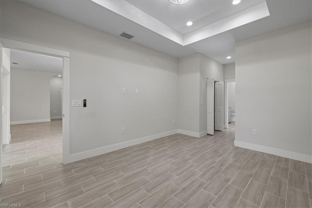 Spare room featuring recessed lighting, a tray ceiling, wood tiled floors, and arched walkways