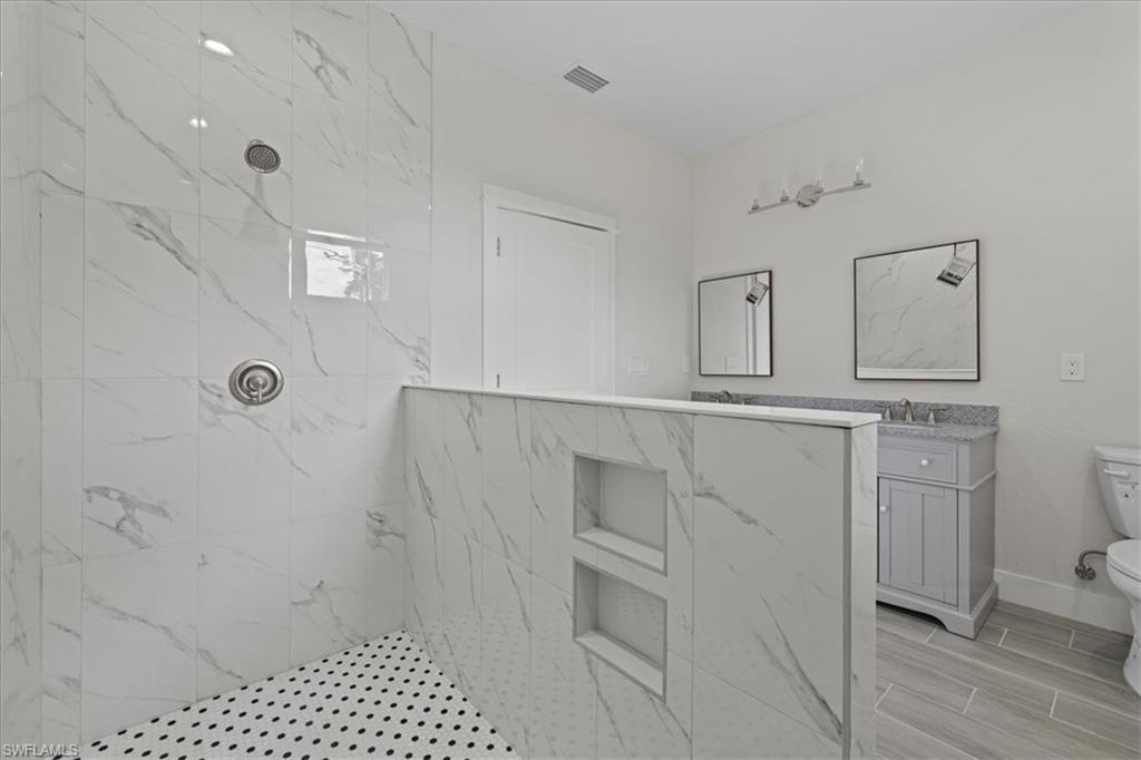 Full bathroom featuring a marble finish shower, vanity, and wood finish floors