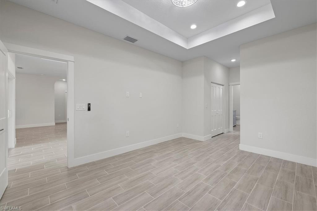 Unfurnished room featuring recessed lighting, a tray ceiling, and wood tiled floors