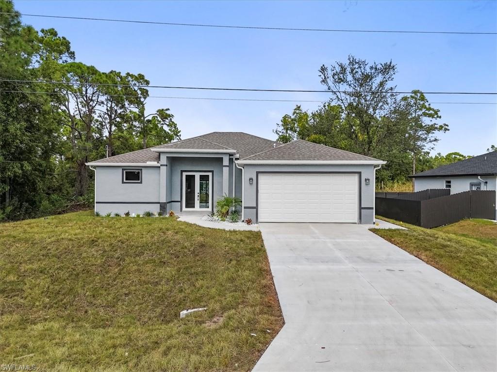 View of front of home with stucco siding, concrete driveway, a garage, french doors, and a shingled roof