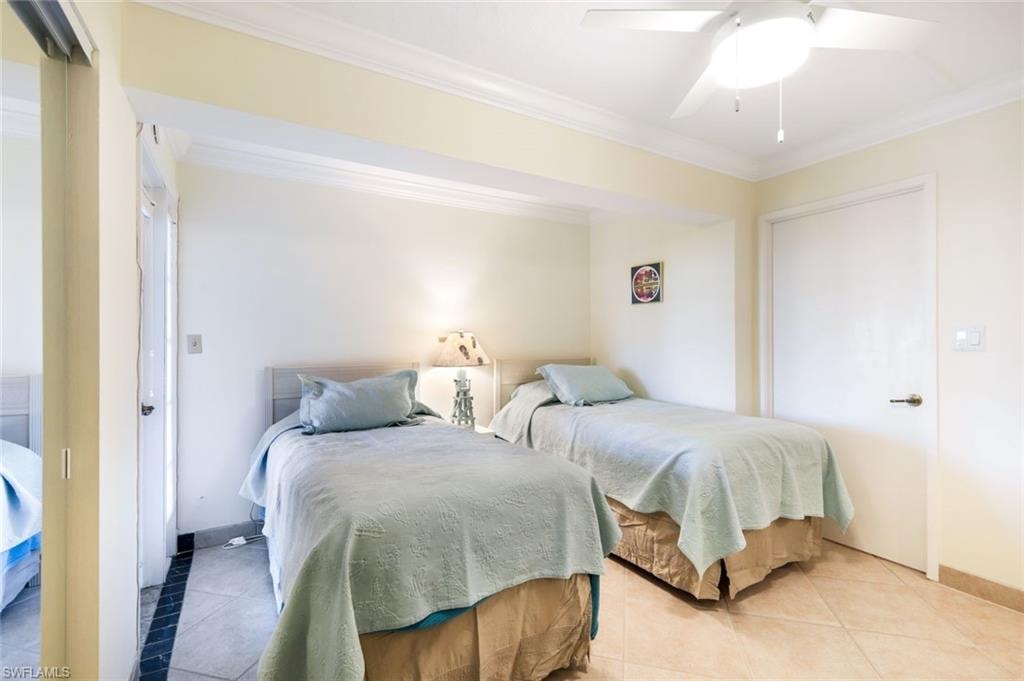 Tiled bedroom featuring a closet, crown molding, and a ceiling fan