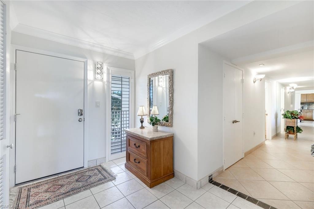 Entrance foyer featuring light tile patterned flooring and crown molding