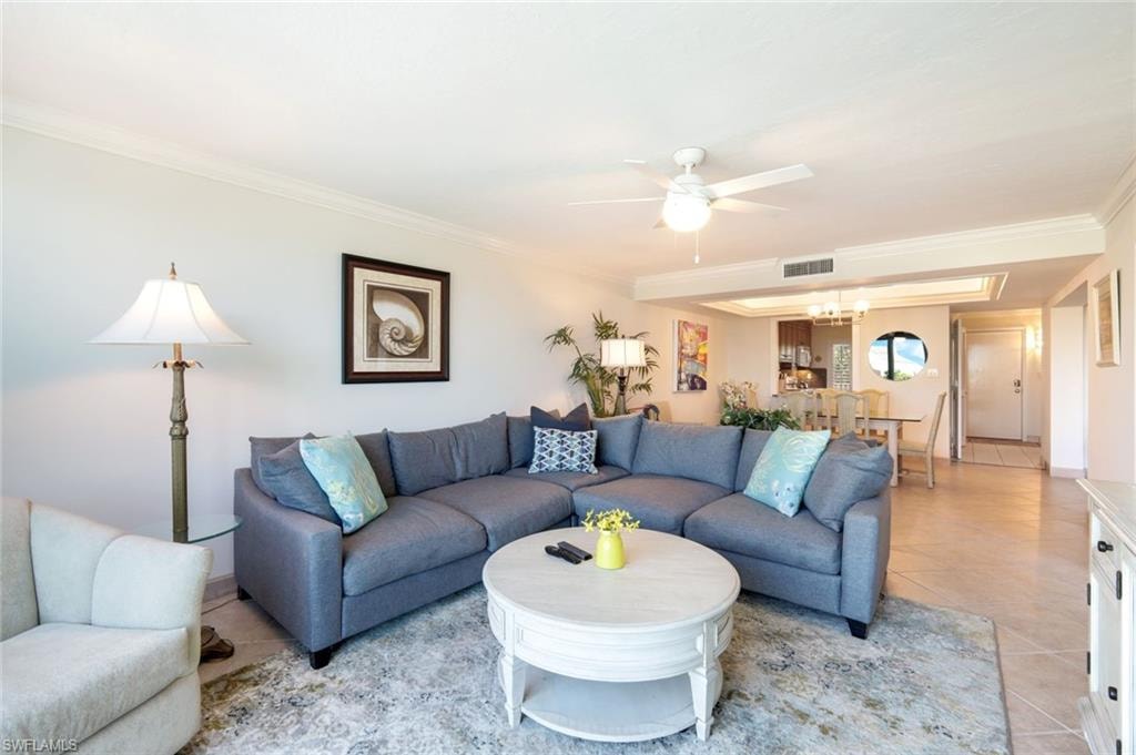 Living area featuring light tile patterned floors, ceiling fan, ornamental molding, and a chandelier