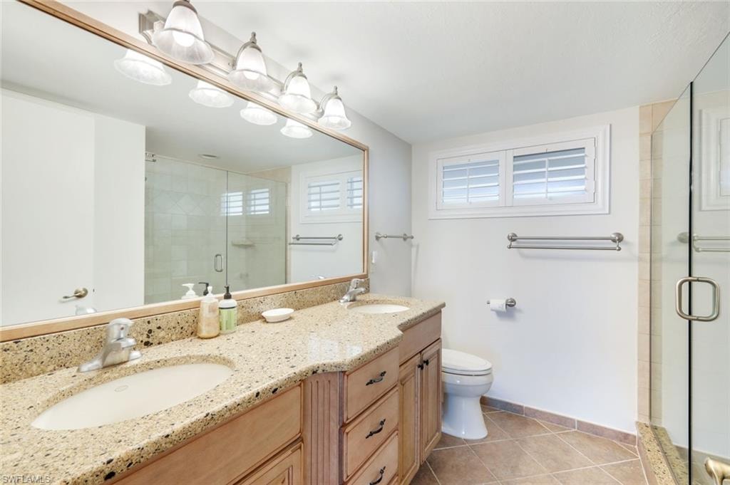 Full bathroom with double vanity, light tile patterned flooring, and a stall shower