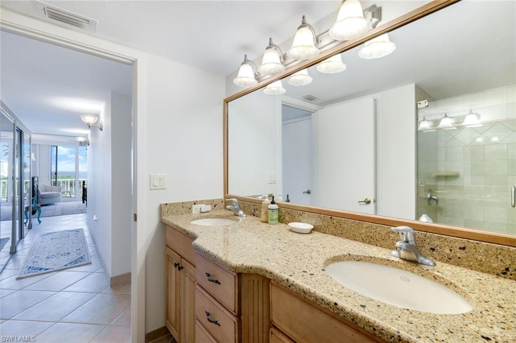 Bathroom featuring double vanity, light tile patterned floors, and a stall shower