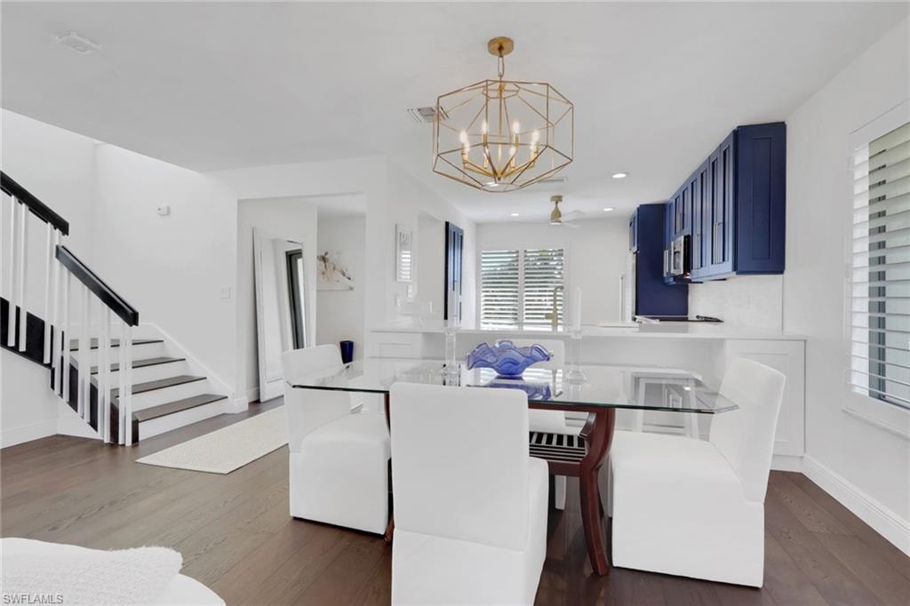 Dining space with dark wood finished floors, a chandelier, stairway, and recessed lighting