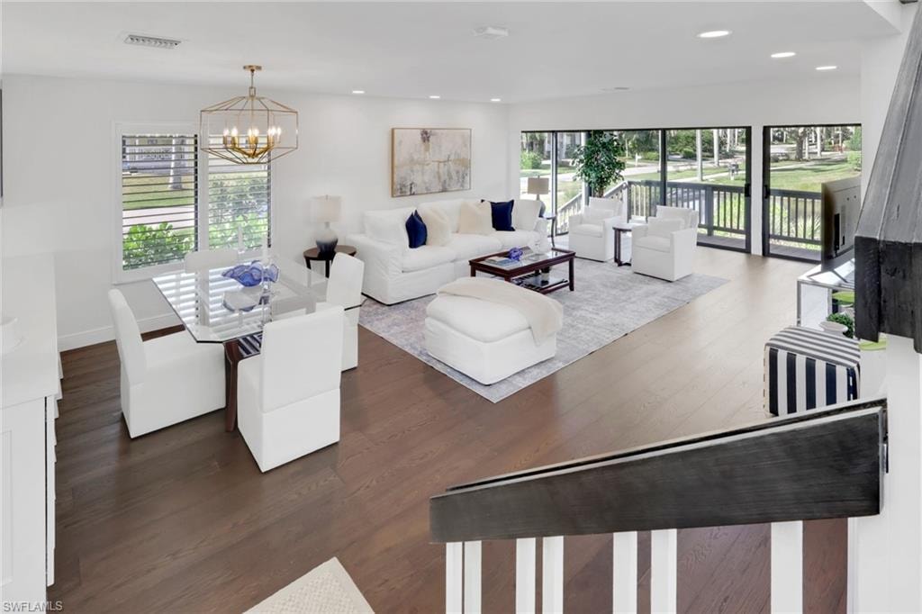 Living room with dark wood finished floors, a chandelier, and recessed lighting